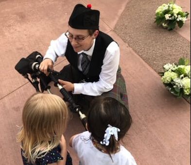 Bagpiper explaining bagpipes to kids at party 