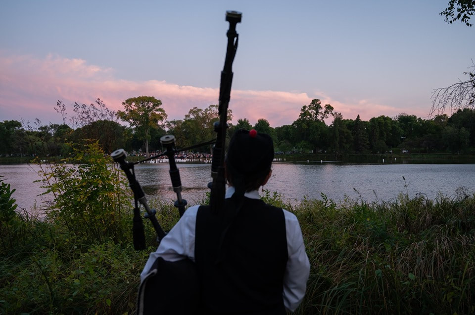 Bagpiping as families at Lakewood Cemetery release lanterns into the pond at sunset to remember loved ones, Minneapolis, MN.
